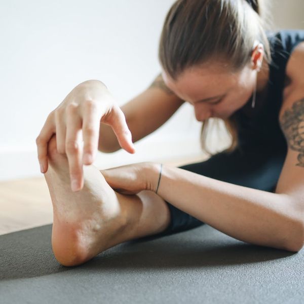 Person practicing a gentle stretching exercise on a mat indoors.